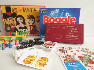 Verschillende gezelschapsspellen, waaronder Malefiz, Boggle en kaarten, liggen dicht bij elkaar.