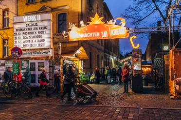 View of the entrance to Christmas at the Cross with illuminated advertising and visitors in the evening
