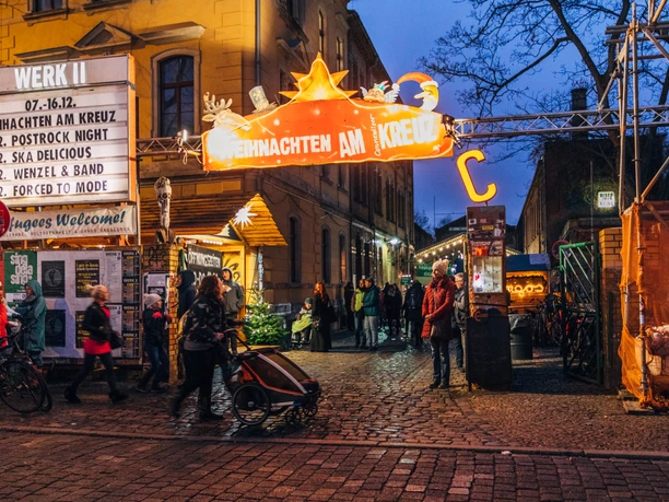 Weihnachtsmarkt am Connewitzer Kreuz - Weihnachten in Leipzig Blick auf den Eingang zum Weihnachten am Kreuz mit Leuchtreklame und Besuchern am Abend