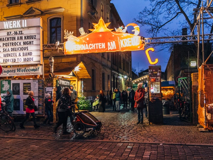 Weihnachtsmarkt am Connewitzer Kreuz - Weihnachten in Leipzig Blick auf den Eingang zum Weihnachten am Kreuz mit Leuchtreklame und Besuchern am Abend