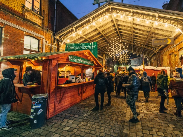 View of a mulled wine stand in front of the illuminated backdrop at Connewitzer Kreuz in the evening