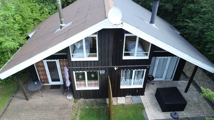 Ferienpark Extertal_Haus Kristin Holzferienhaus mit doppeltem Giebeldach, Veranda und Terrasse im grünen Waldgebiet, ruhig gelegen.