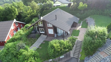 Ferienpark Extertal_Haus Sonnenhügel Ferienhaus mit Holzfassade und Terrasse, umgeben von Grünflächen und angrenzenden Häusern im Extertal.