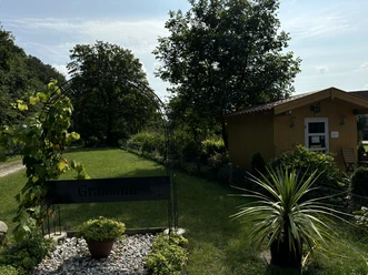 Hofladen Gramann ©Emsland Tourismus GmbH Eingangsbereich des Hofladens Gramann mit Gartenpfad, Pflanzenbogen und kleinem gelbem Holzhaus.