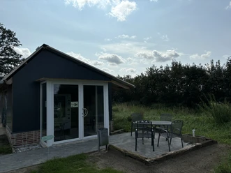 Knues Regiomat ©Emsland Tourismus GmbH Kleines Verkaufsgebäude mit Glasfront, davor Sitzplatz mit Metalltisch und vier Stühlen im Grünen
