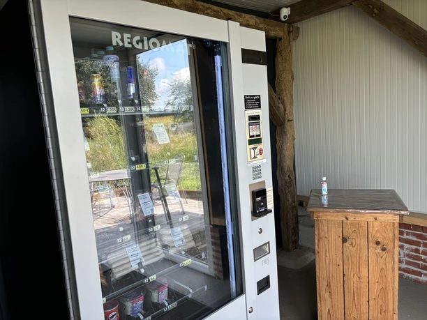 Knues Regiomat ©Emsland Tourismus GmbH Regiomat mit regionalen Lebensmitteln und Getränken neben Holztisch in überdachter Hofecke