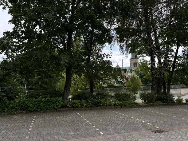 Stellplatz Parkplatz Ortskern ©Emsland Tourismus GmbH Gepflasterter Parkplatz mit Bäumen und Blick auf eine Kirche im Zentrum von Salzbergen