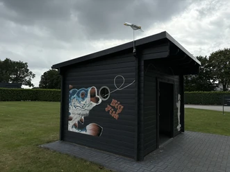 Regiomat KDH-Fishing ©Emsland Tourismus GmbH Kleines schwarzes Holzhaus mit bunter Fischmalerei und Schriftzug Big Fish auf grünem Rasen.