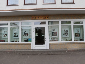 Ansicht Spielzeugmuseum Vorderansicht des Spielzeugmuseums mit großen Fenstern und bunter Spielzeugaustellung.