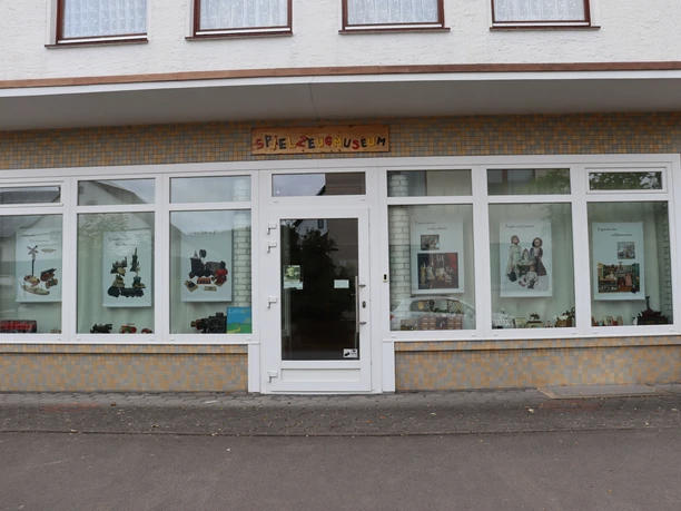 Ansicht Spielzeugmuseum Vorderansicht des Spielzeugmuseums mit großen Fenstern und bunter Spielzeugaustellung.