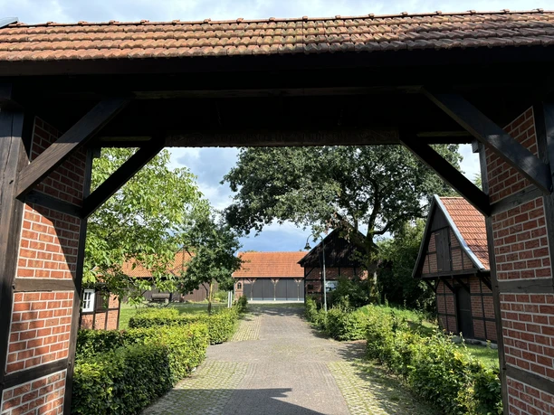 Heimathof Bramsche ©Emsland Tourismus GmbH Eingangsportal mit Fachwerk und Blick auf historische Backsteinhäuser im grünen Hofensemble.