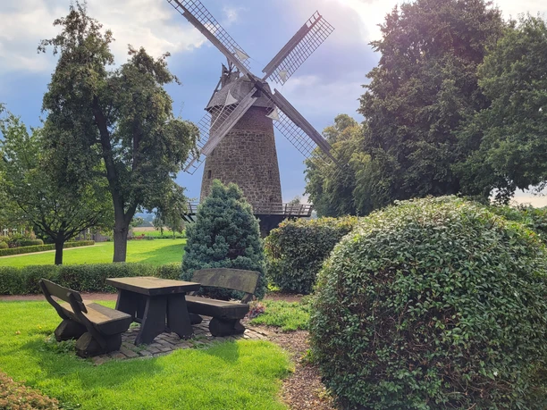 Königsmühle Eilhausen Königsmühle Eilhausen, historische Windmühle in grüner Umgebung, mit Bänken und Tisch im Vordergrund.
