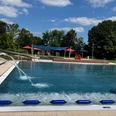 Freibad mit breitem Einstieg, Sprungturm, viel Grün und schattigen Bereichen für entspannte Stunden.