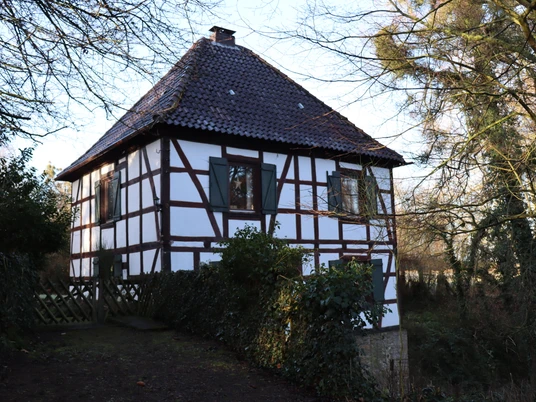 Gut Obernfelde Fachwerkgebäude mit roten Dachziegeln, umgeben von Bäumen; ruhige ländliche Atmosphäre.