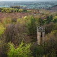 Wartturm Ein alter, steinernem Turm steht umgeben von einem herbstlich gefärbten Wald im Vordergrund.
