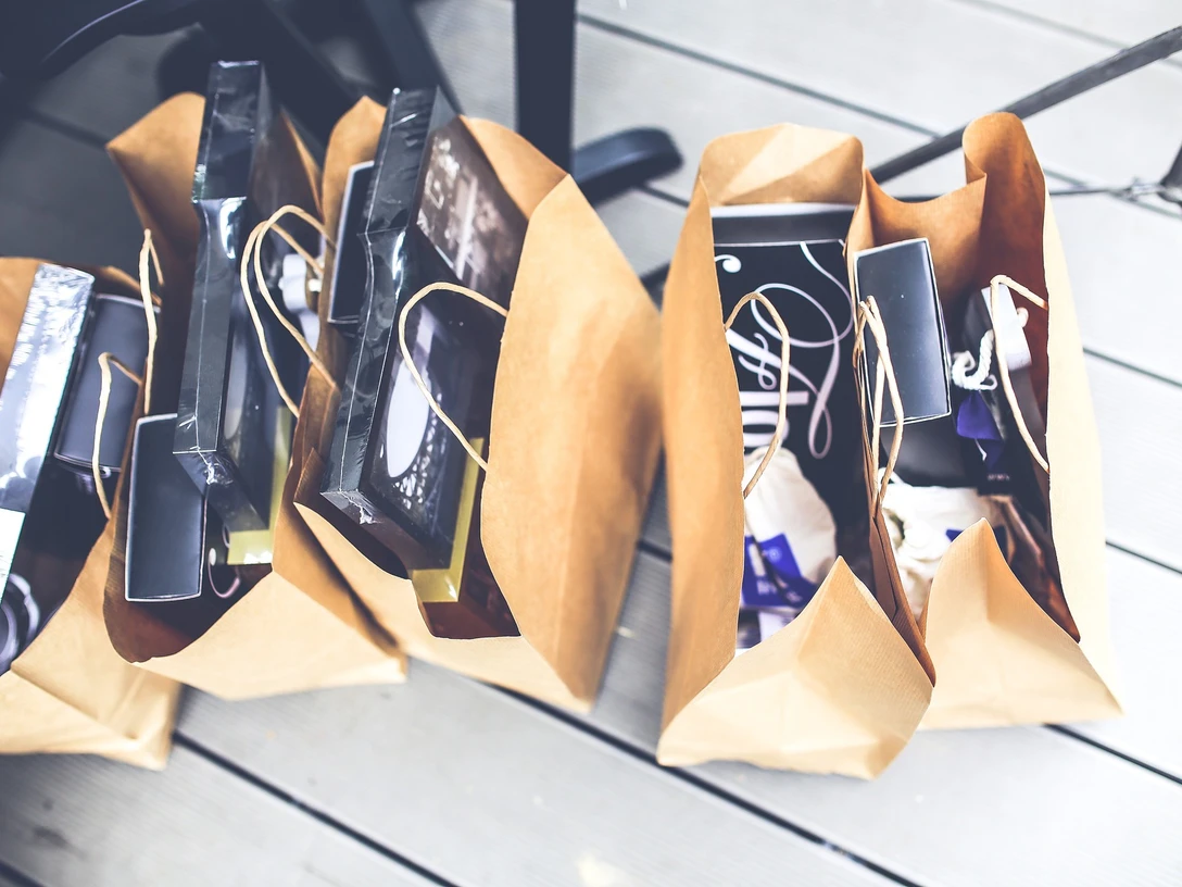 Verkaufsoffener Sonntag.jpg Mehrere Einkaufstüten aus braunem Papier, die auf einem Holzfußboden stehen, gefüllt mit diversen Artikeln.Several shopping bags made of brown paper, standing on a wooden floor, filled with various items.Flere indkøbsposer af brunt papir står på et trægulv, fyldt med forskellige ting.Verschillende boodschappentassen van bruin papier staan op een houten vloer, gevuld met verschillende artikelen.