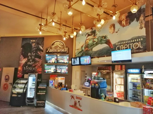 Foyer des Capitol-Kinos mit Snacks Theke, Kinoplakaten und beleuchteten Dekoelementen an der Decke.
