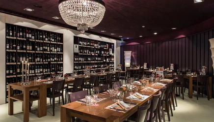 Stilvoller Gastraum des Ristorante uno e più mit gedeckten Tischen und großer Weinwand