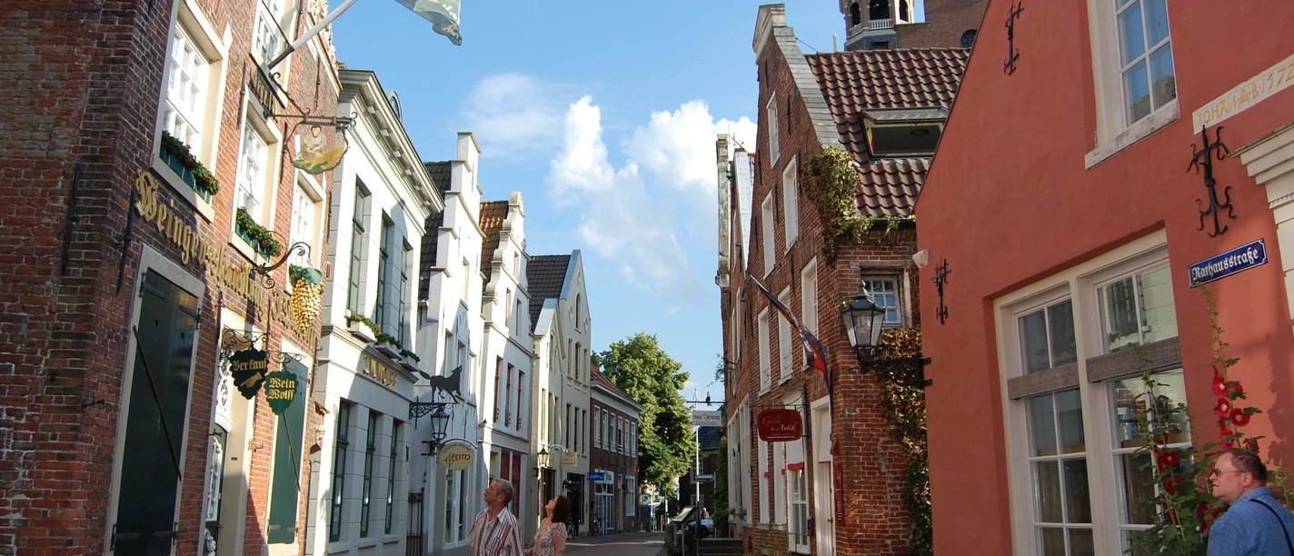 2106_altstadt_von_leer-original Cobbled alley in the old town of Leer with historic brick houses and passers-by in the sun.