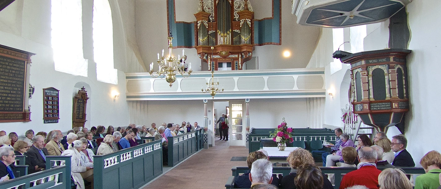 Kirche in Uttum Innenraum der Kirche in Uttum. Menschen sitzen in den Kirchenbänken. Blick auf die schöne Orgel.