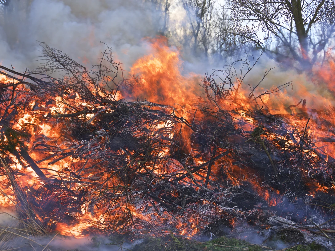 Osterfeuer Brennendes Osterfeuer mit hohen Flammen, dichter Rauch über Zweigen und Ästen im Freien.