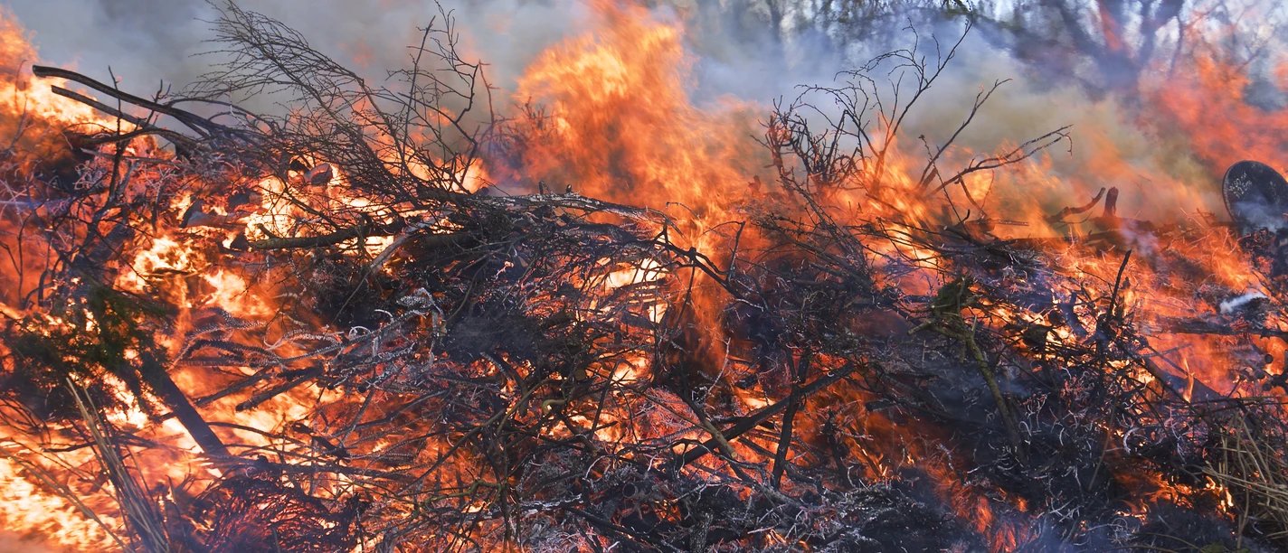 Osterfeuer Brennendes Osterfeuer mit hohen Flammen, dichter Rauch über Zweigen und Ästen im Freien.