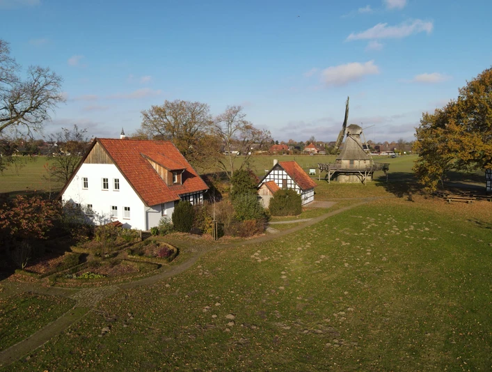 Ländliche Szene mit einer traditionellen Mühle und historischen Fachwerkhäusern im Grünen.
