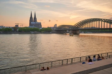 Rheinboulevard Panoramablick auf den Rheinboulevard mit dem Kölner Dom und der eindrucksvollen Hohenzollernbrücke im Sonnenuntergang.