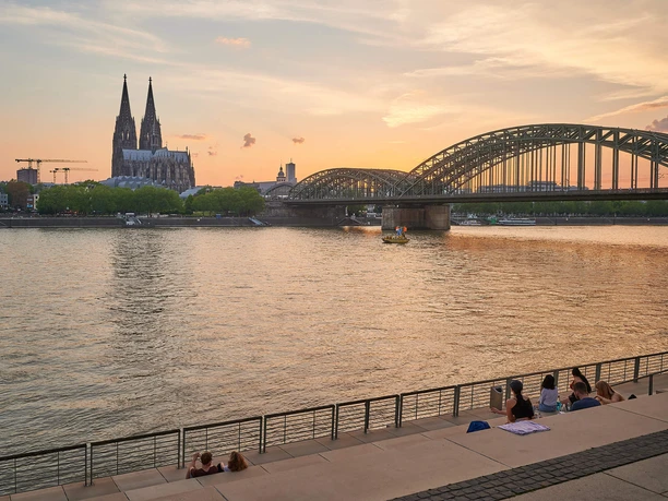 Rheinboulevard Panoramablick auf den Rheinboulevard mit dem Kölner Dom und der eindrucksvollen Hohenzollernbrücke im Sonnenuntergang.