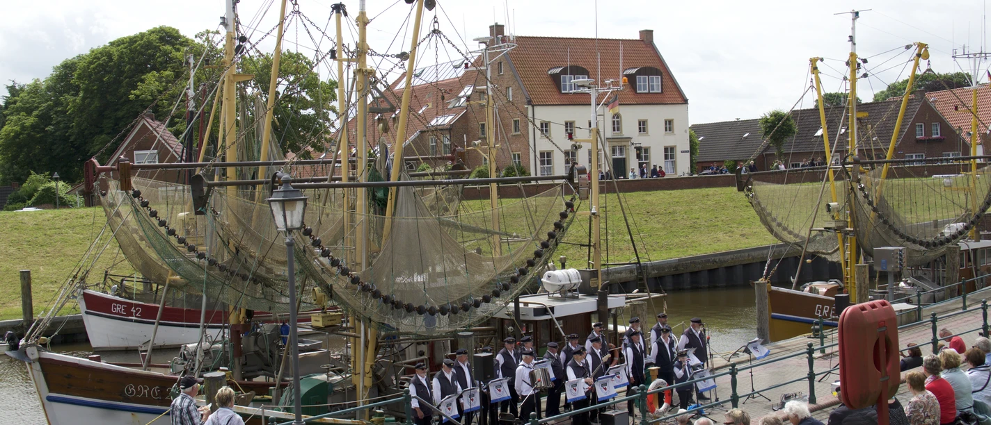 Sonntagskonzert im Hafen Greetsiel Ein Shanty-Chor singt vor historischen Krabbenkuttern im Hafen von Greetsiel für zahlreiches Publikum.