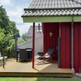 Ferienpark Extertal_Das Waldhaus Ein rotes Holzhaus mit Terrasse, Gartenmöbeln und Liegestühlen, umgeben von grüner Natur.