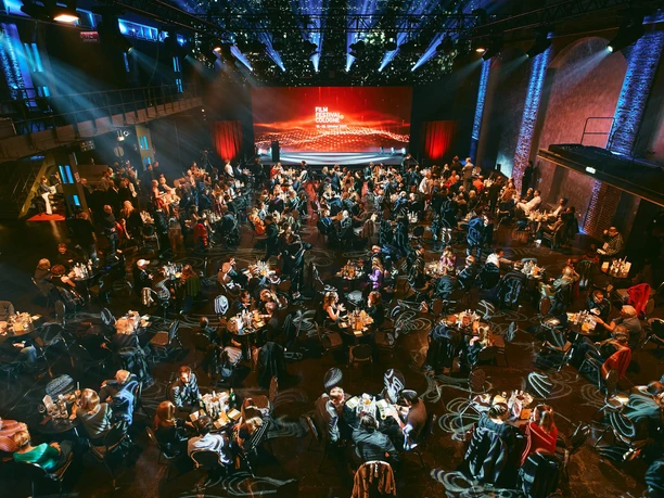 Film Festival Cologne Ein festlich beleuchteter Saal voller runder Tische und eleganter Gäste beim Film Festival Cologne.