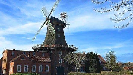 Mühle Pewsum Historische Backstein-Windmühle in Pewsum unter blauem Himmel.