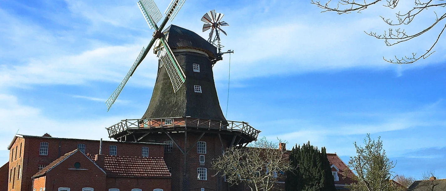 Mühle Pewsum Historische Backstein-Windmühle in Pewsum unter blauem Himmel.