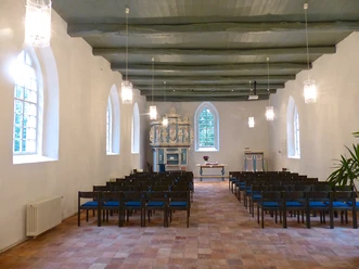 Kirche in Jennelt Heller Kirchenraum mit Holzbalkendecke, Stuhlreihen und einer blau-goldenen Orgel im Altarbereich.