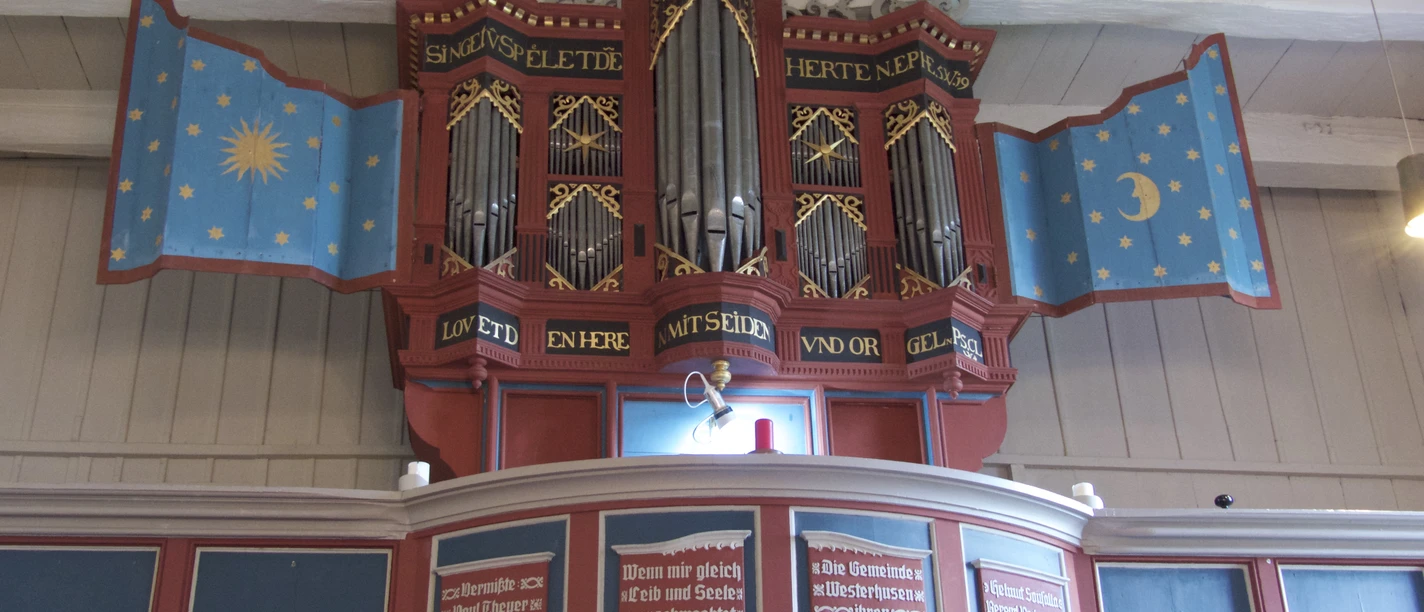 Kirche Westerhusen Historische Orgel der Kirche Westerhusen mit blauen, sternenverzierten Flügeln.