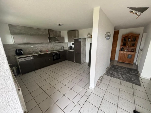 Küche_Flur.jpg Moderne Küche mit grauen Einbauschränken, Herd und Kühlschrank, angrenzend an Flur mit Sideboard.