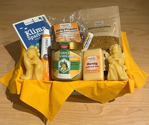 Imkerei Rensen ©Emsland Tourismus GmbH (2).png Geschenkset mit Honig, Blütenpollen, Bonbons, Seife und Bienenwachskerzen auf gelbem Tuch