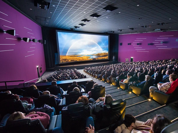 GRENZGANG in the Cinedom People in a large movie theater watch an impressive projection on a big screen.