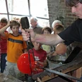 Glasmacher.jpg Ein Glasmacher fertigt vor einer staunenden Kindergruppe eine leuchtend rote Glaskugel an.