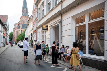 Kunstverein Lüneburg Menschen vor dem Gebäude des Kunstvereins Lüneburg, im Hintergrund die St. Nicolaikirche.