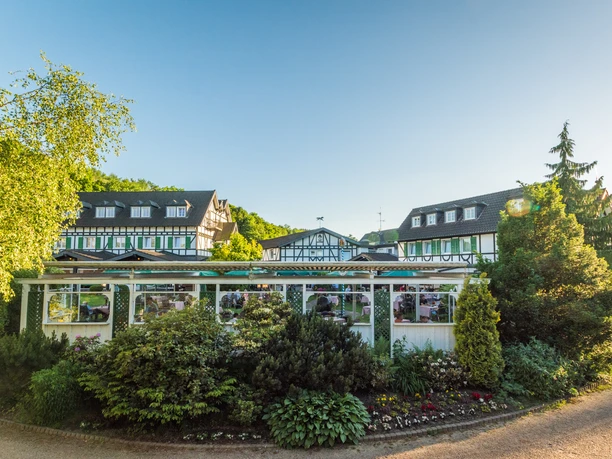 Lohmanns Romantik Hotel Gravenberg in Langenfeld Ein elegantes Fachwerkhotel umgeben von üppigem Grün unter strahlend blauem Himmel.