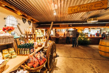 An old barn with a cart full of products. In the background there is a chandlery and a Christmas tree.