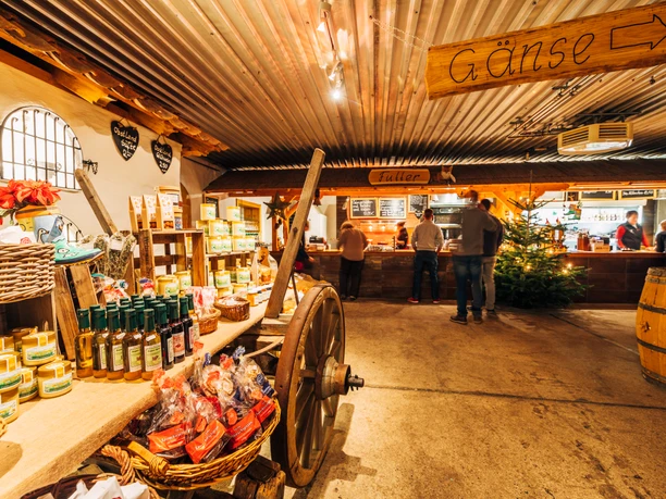 Gänsemarkt Eskildsen in Wermsdorf Eine alte Scheune in dem ein Wagen mit Produkten steht. Im Hintergrund ist eine Auschanlstation und ein Weihnachtsbaum.