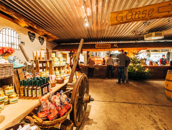 Gänsemarkt Eskildsen in Wermsdorf Eine alte Scheune in dem ein Wagen mit Produkten steht. Im Hintergrund ist eine Auschanlstation und ein Weihnachtsbaum.