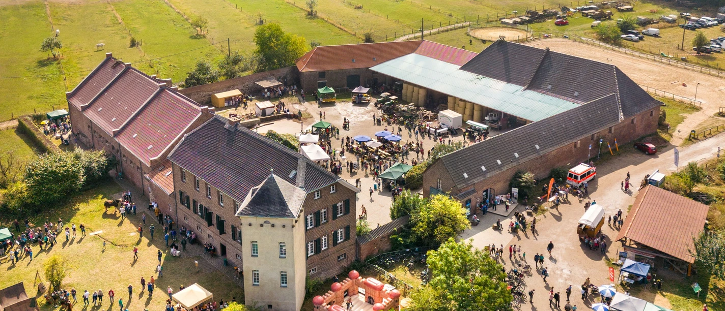 Luftaufnahme von Haus Bürgel, einem historischen Anwesen mit grünen Wiesen und befestigten Wegen.