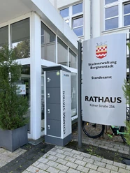 Ladeschrank Eingang des Rathauses mit einem E-Ladestationsschrank und einem Hinweisschild zur Stadtverwaltung.