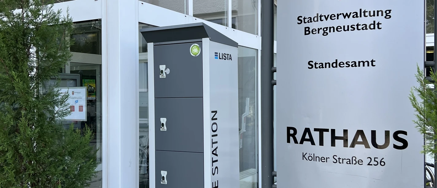 Ladeschrank Eingang des Rathauses mit einem E-Ladestationsschrank und einem Hinweisschild zur Stadtverwaltung.