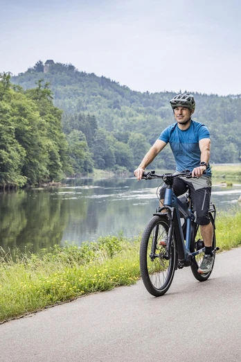 Radfahrer am Regental-Radweg Zwei Radfahrer fahren auf einem geteerten Abschnitt entlang des Regental-Radwegs. Im Hintergrund sieht man den Regen und die Burg Stockenfels.