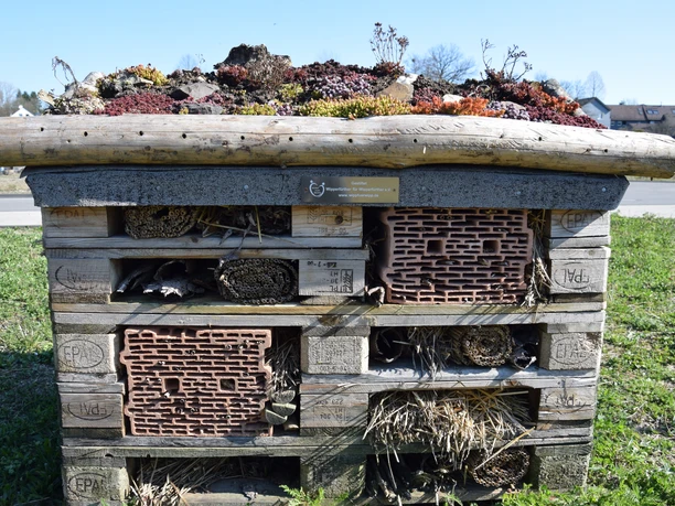 Insektenhotel Insektenhotel aus Holz und Ziegeln auf einer Wiese in Wipperfürth unter blauem Himmel.